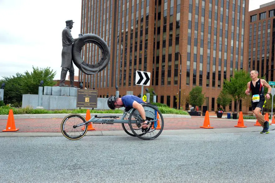 Adaptive athlete wheeling past the Rubber worker statue